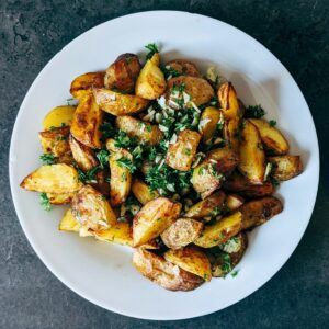 a white plate topped with potatoes and greens