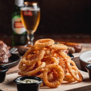 Crispy onion rings served with dipping sauces and beer.