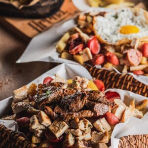 Basket of meat, fries, and sausages with fried egg